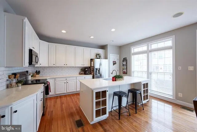 a kitchen with stainless steel appliances a dining table chairs stove refrigerator and cabinets