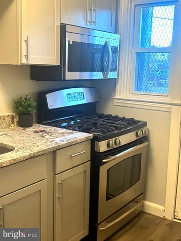 a kitchen with granite countertop a stove and a white cabinet