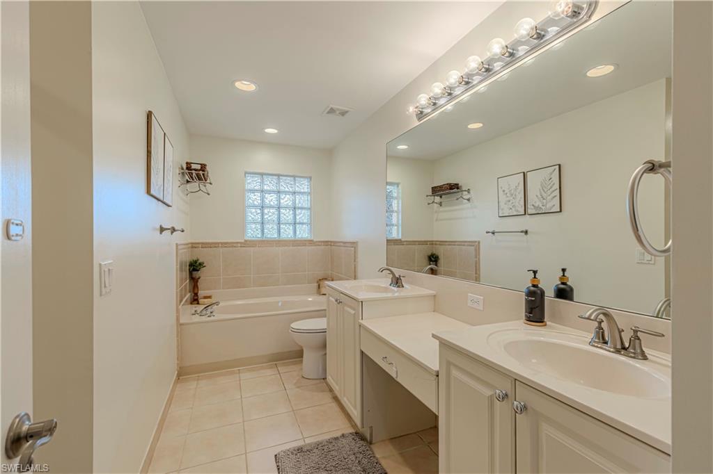 1767 Ribbon Fan Lane Naples, FL 34119 - Photo 10 of 31 Bathroom featuring a tub to relax in, vanity, tile patterned flooring, and toilet