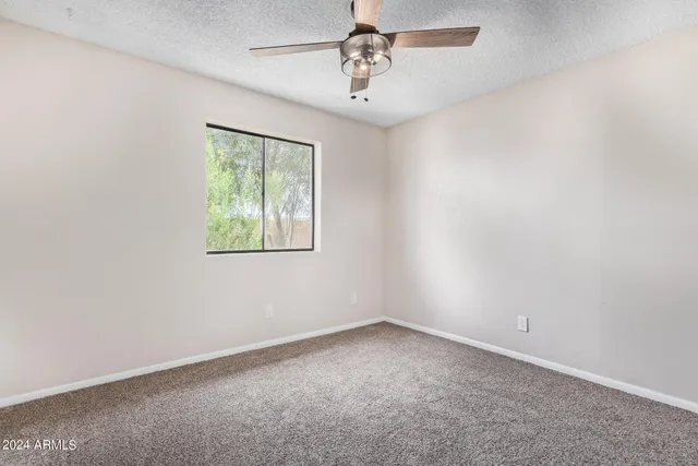 an empty room with a window and a ceiling fan