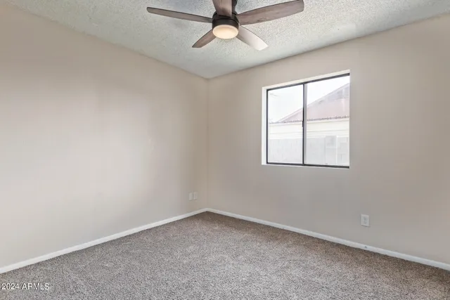an empty room with a window and a ceiling fan