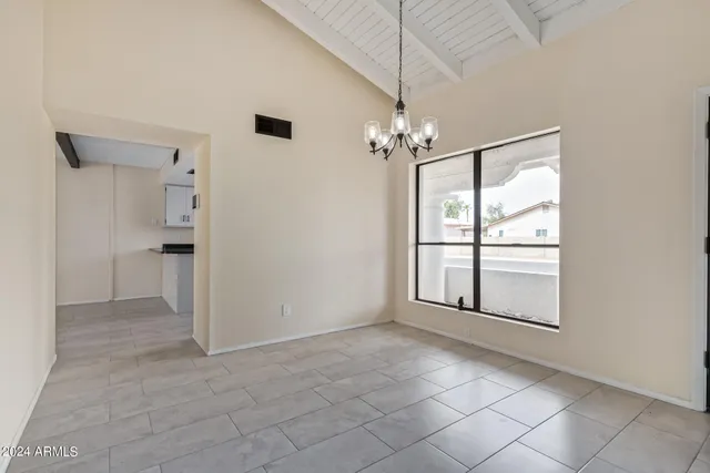 an empty room & chandelier fan and windows