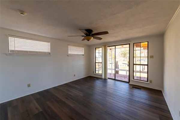 an empty room with wooden floor and windows