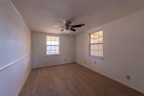 an empty room with windows and ceiling fan