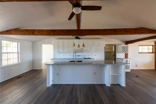 a kitchen with stainless steel appliances granite countertop a sink dishwasher a stove a refrigerator wooden floor and cabinets