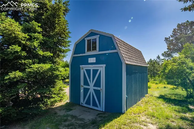 a front view of a house with a yard and a large tree