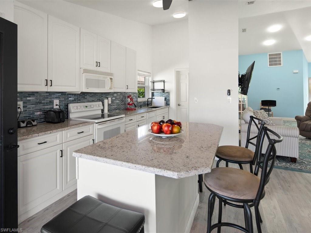 360 Fox Den Circle Naples, FL 34104 - Photo 12 of 41 a kitchen with stainless steel appliances granite countertop white cabinets and chairs