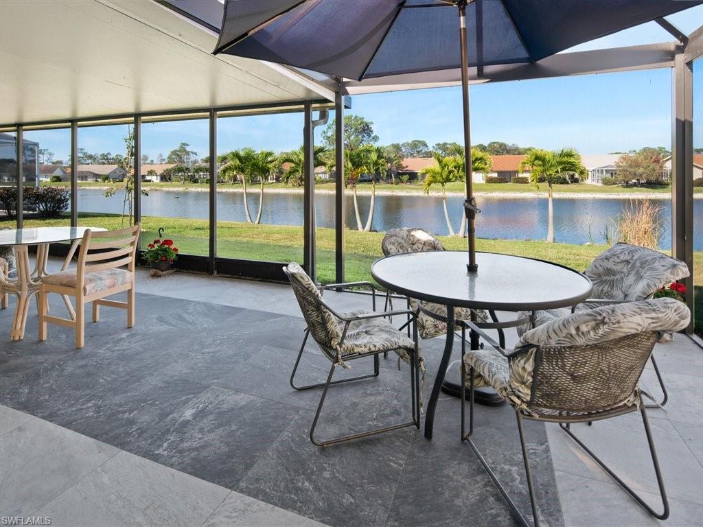 360 Fox Den Circle Naples, FL 34104 - Photo 15 of 41 a view of a swimming pool with a table and chairs under an umbrella