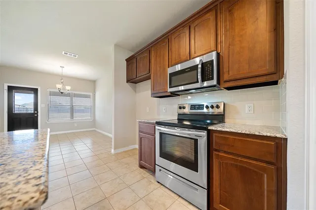 a kitchen with stainless steel appliances granite countertop a stove a microwave and a sink