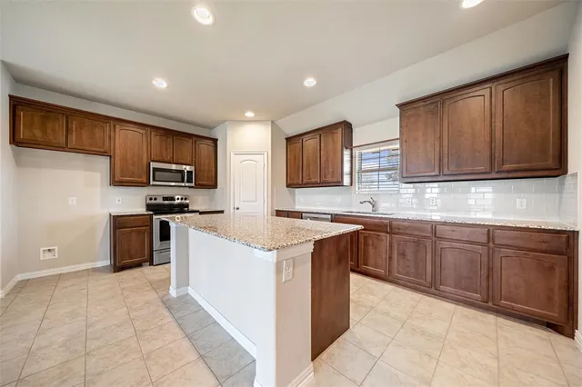 a kitchen with kitchen island granite countertop wooden cabinets stainless steel appliances and a counter space