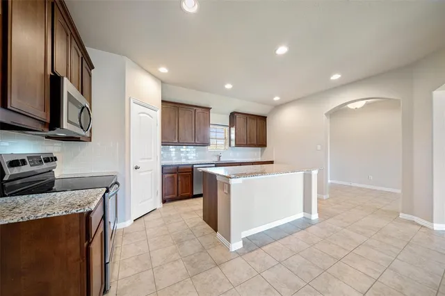 a large kitchen with stainless steel appliances granite countertop a stove a sink and a microwave