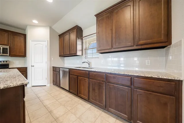 a kitchen with stainless steel appliances granite countertop wooden cabinets a sink and dishwasher