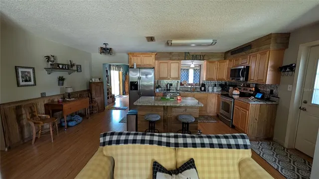 a kitchen with stainless steel appliances wooden floor dining table and chairs