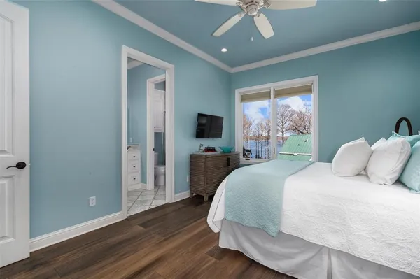 a spacious bedroom with a bed and a flat tv screen on dresser