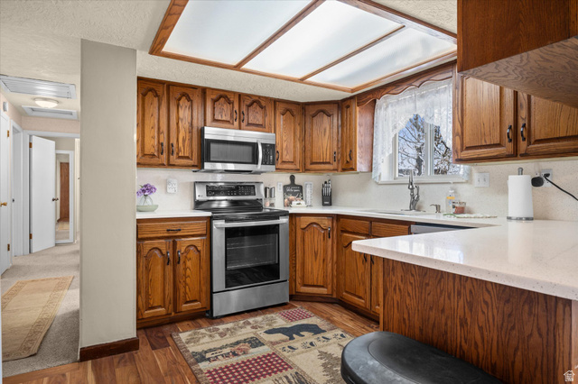 2298 West 800 North Clinton, UT 84015 - Photo 10 of 53 Kitchen with wood finish cabinets, stainless steel appliances, dark wood finished floors, and light stone countertops