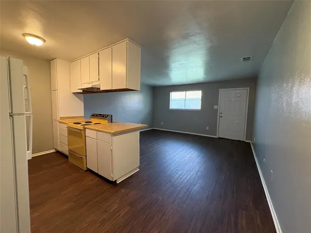 a kitchen with hard wood floors and white cabinets