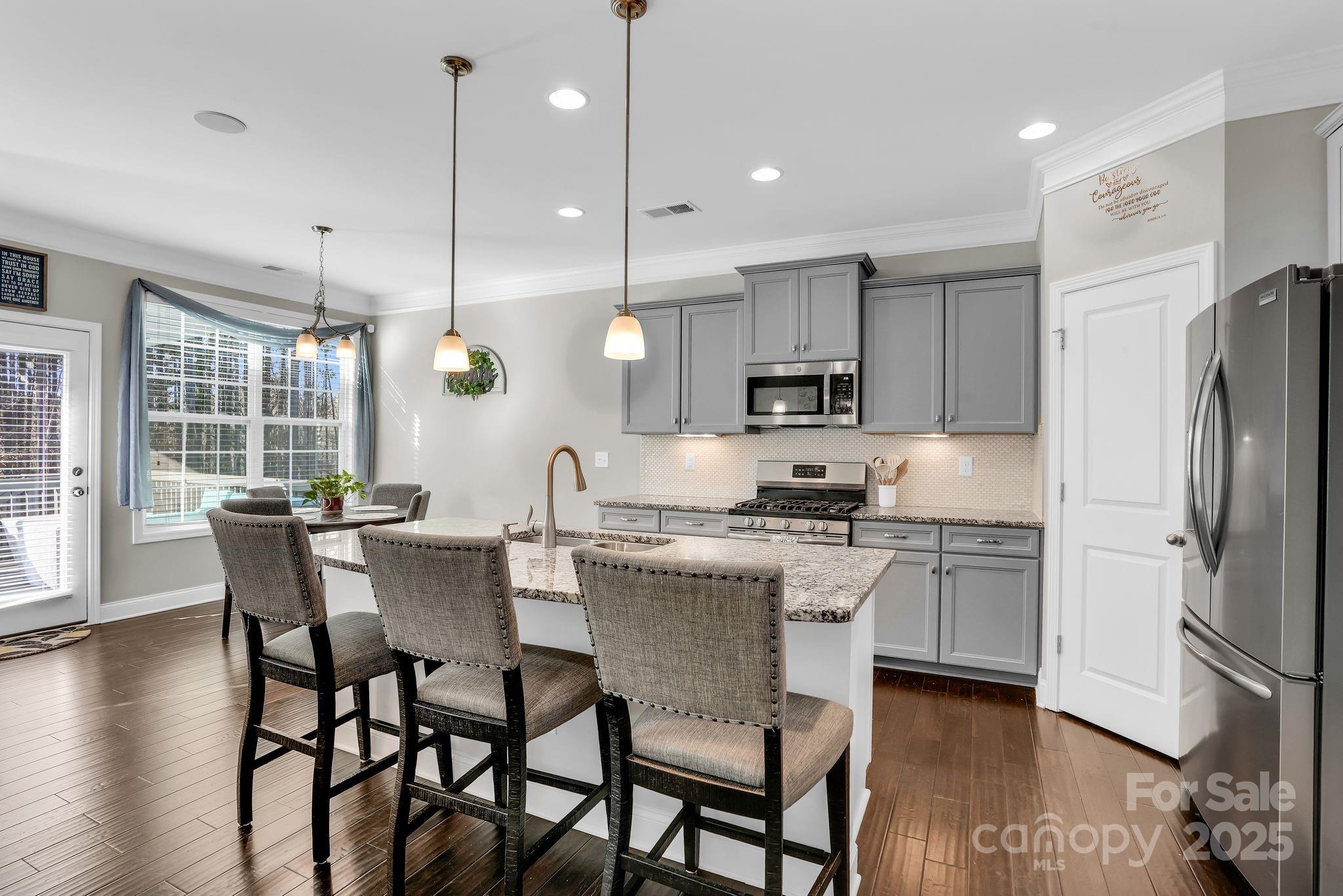 9507 Inverness Bay Road Charlotte, NC 28278 - Photo 8 of 29 a kitchen with stainless steel appliances granite countertop a stove a refrigerator a kitchen island a dining table and chairs with wooden floor