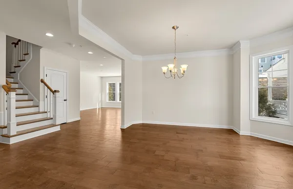 an empty room with wooden floor chandelier and windows