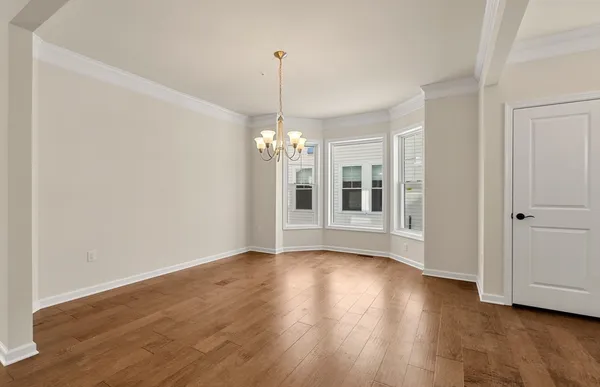 a view of an empty room with window and wooden floor