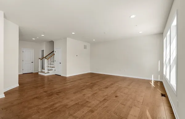 an empty room with wooden floor and natural light