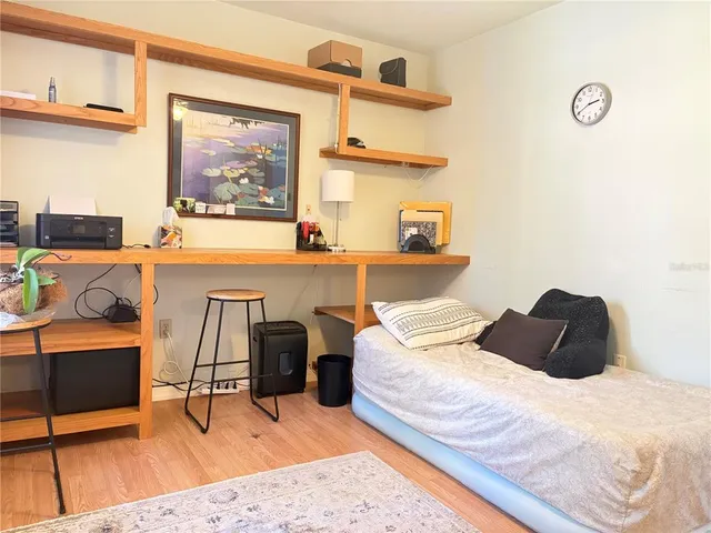 a bedroom with a bed a desk and chair with the wooden floor