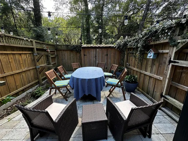 a view of a patio with couches table and chairs and potted plants with wooden floor and fence