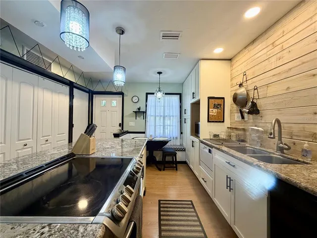 a large kitchen with kitchen island granite countertop a large window and stainless steel appliances