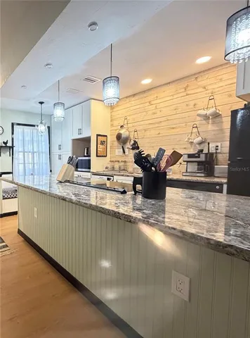 a view of a kitchen with kitchen island a large counter top space a sink stainless steel appliances and cabinets