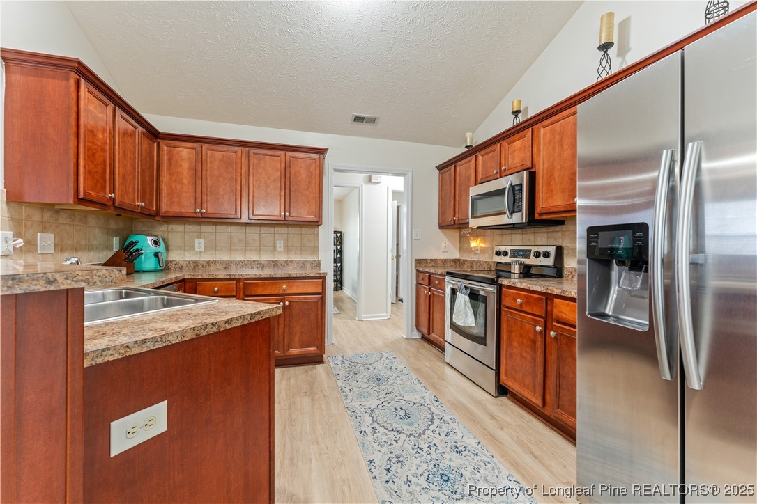292 Falling Leaf Drive Raeford, NC 28376 - Photo 5 of 40 a kitchen with stainless steel appliances granite countertop a stove top oven a sink and dishwasher