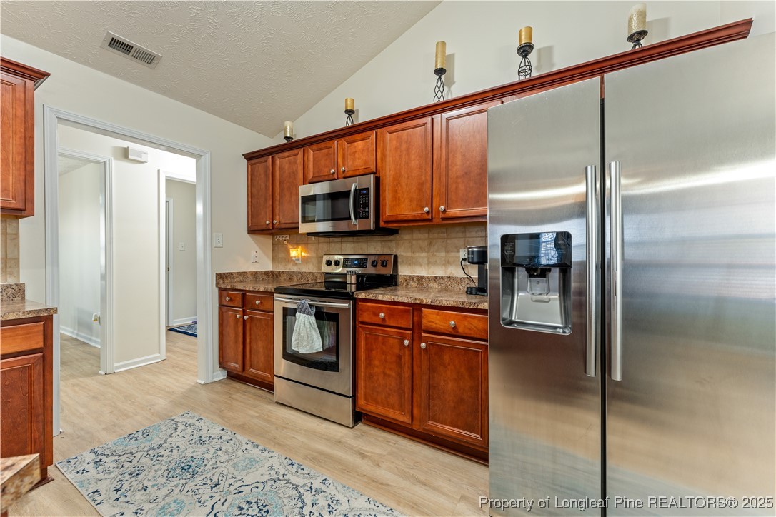 292 Falling Leaf Drive Raeford, NC 28376 - Photo 6 of 40 a kitchen with stainless steel appliances granite countertop a refrigerator a stove and a sink with wooden floor