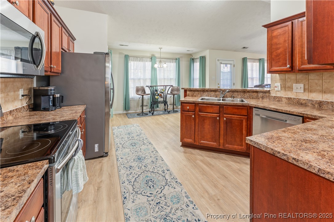 292 Falling Leaf Drive Raeford, NC 28376 - Photo 7 of 40 a kitchen with stainless steel appliances granite countertop wooden cabinets a stove top oven a sink and dishwasher
