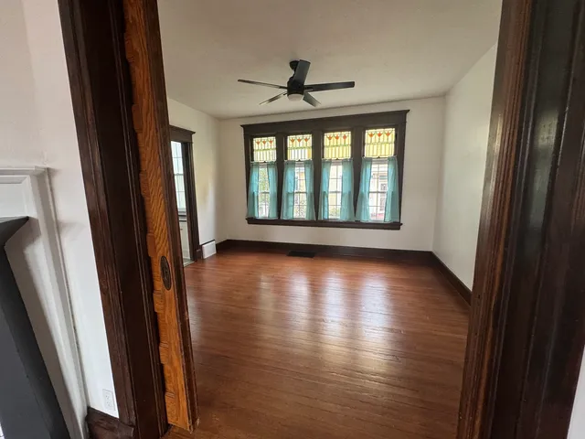 an empty room with wooden floor and windows