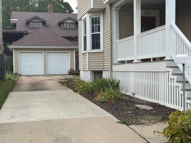 a view of a white house with large windows and a small yard