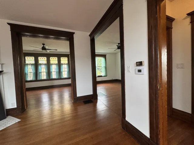 a view of an empty room with wooden floor and a window