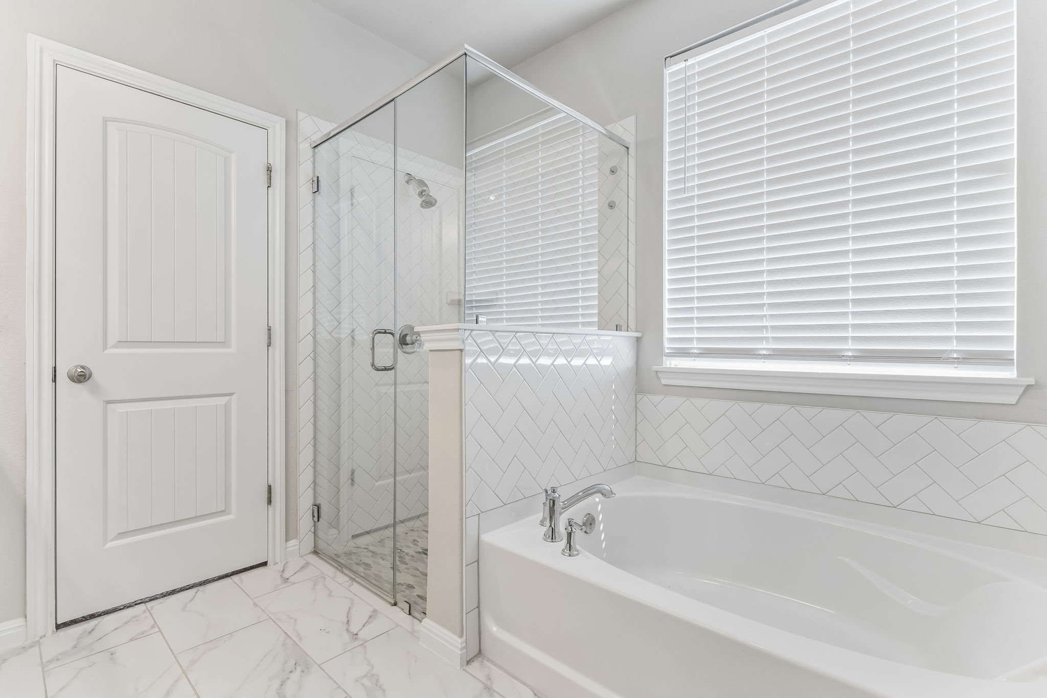 4009 Milano River Road Hutto, TX 78634 - Photo 22 of 40 Marble-style tile flooring anchors a modern bath complete with a soaking tub and glass shower.