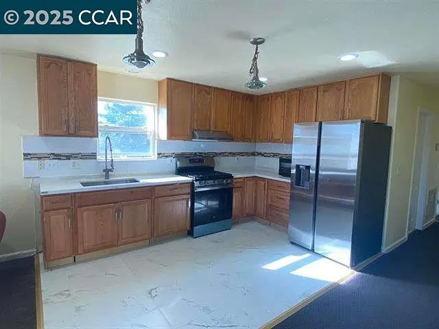 a kitchen with granite countertop a refrigerator a sink and dishwasher