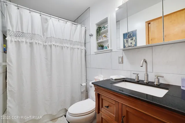 a bathroom with a granite countertop sink a toilet and a mirror