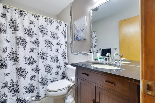 a bathroom with a granite countertop sink a toilet and a mirror