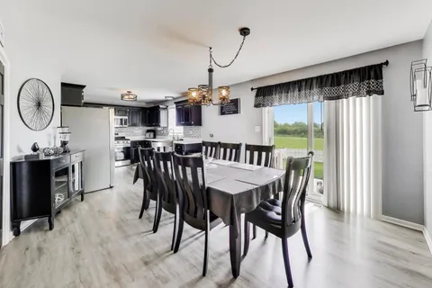 a view of a dining room and livingroom with furniture wooden floor a chandelier