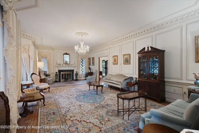 a living room with furniture a chandelier and a bookshelf