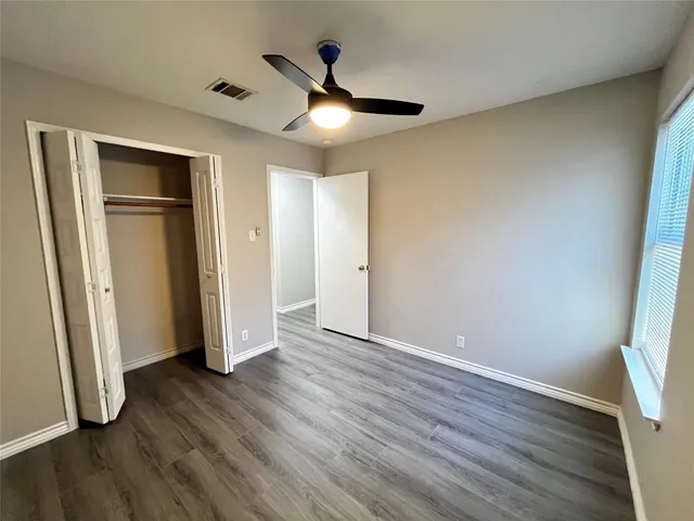 an empty room with wooden floor and a ceiling fan