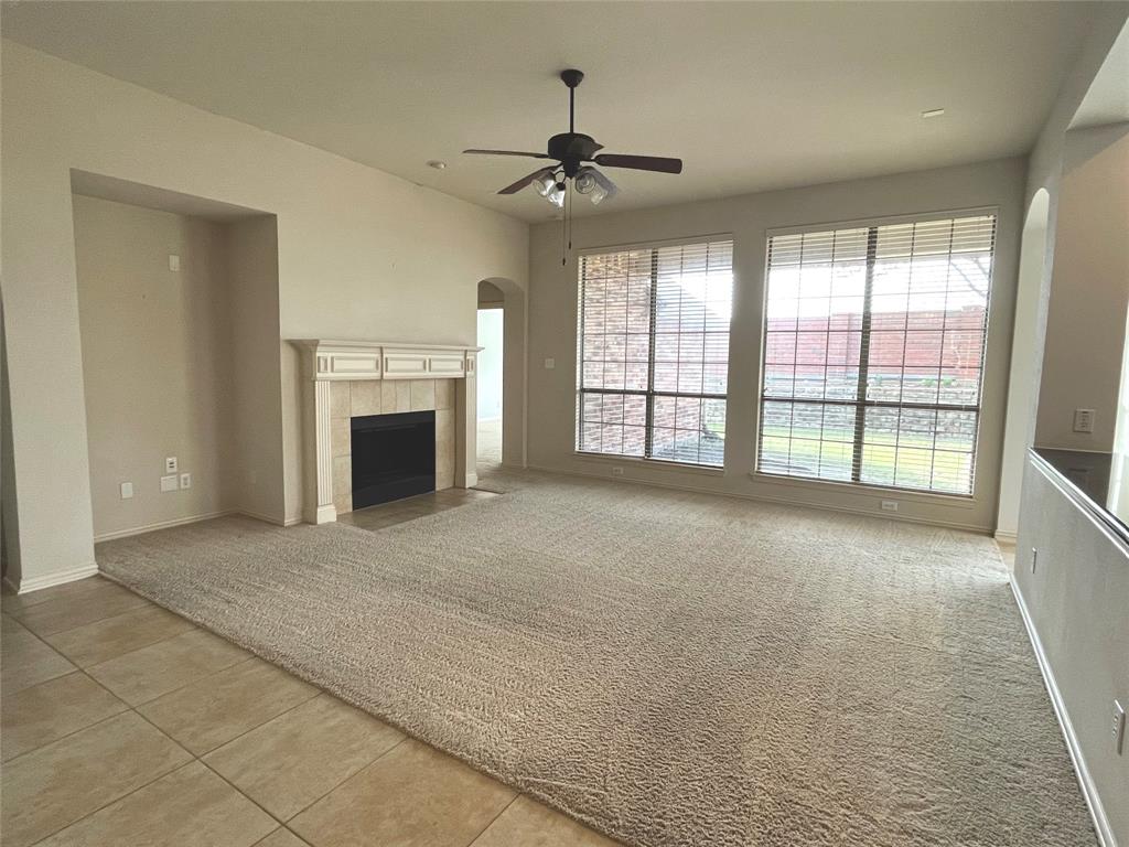 4101 White Porch Road Plano, TX 75024 - Photo 4 of 18 Spacious living area featuring carpet flooring, a ceiling fan, and a tiled fireplace with a decorative mantel