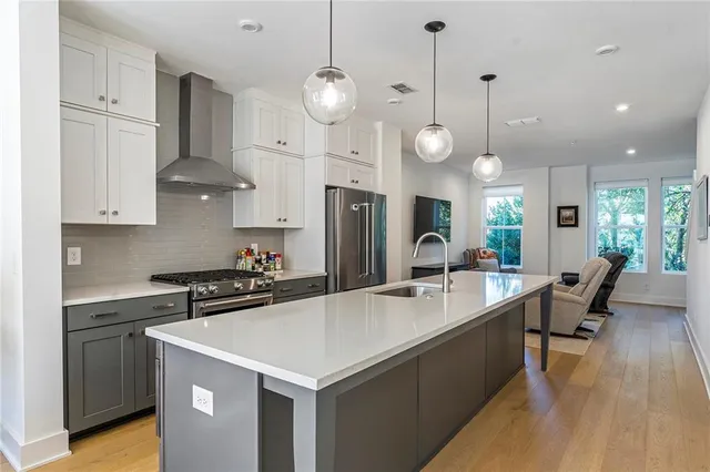 a kitchen with stainless steel appliances granite countertop a sink a refrigerator and a white cabinets