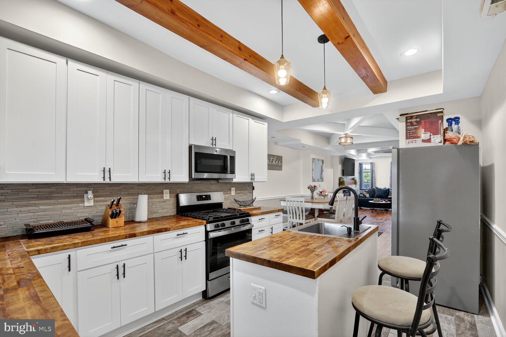 1502 East Hoffman Street Baltimore, MD 21213 - Photo 12 of 30 a kitchen with stainless steel appliances granite countertop a stove top oven a sink a refrigerator and white cabinets with wooden floor