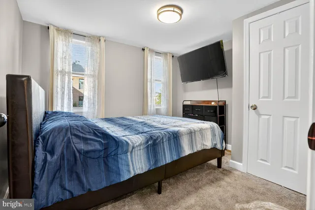 a bedroom with a bed flat screen tv and a refrigerator