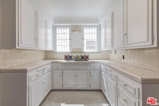 a kitchen with stainless steel appliances a refrigerator and white cabinets