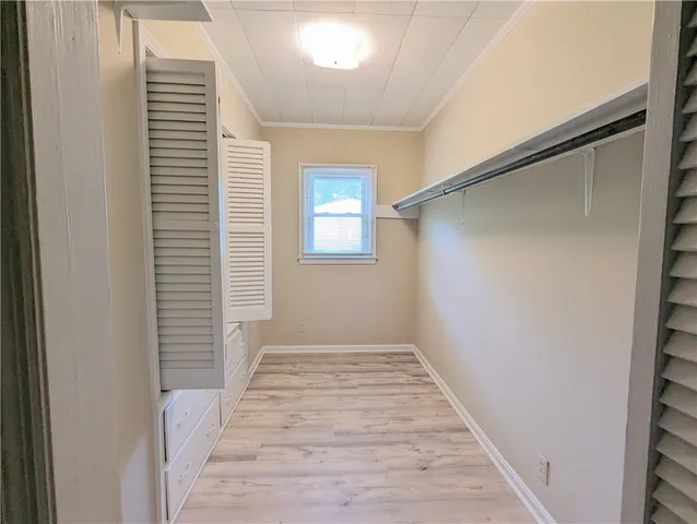 a view of a hallway with wooden floor and a bathroom