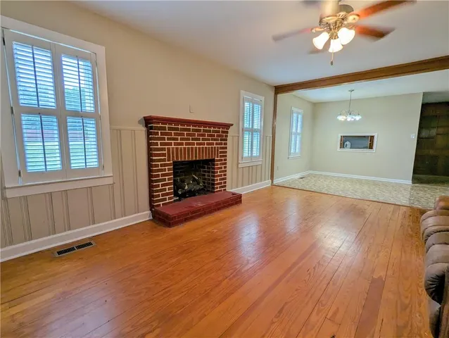 an empty room with wooden floor fireplace and windows