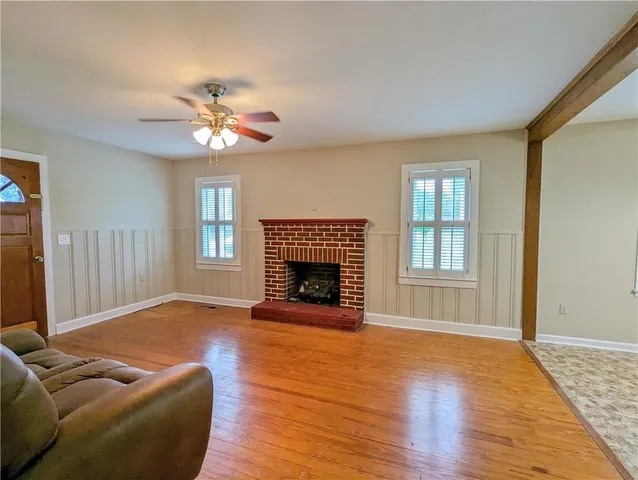 a view of a livingroom with a fireplace a ceiling fan and windows