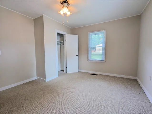 an empty room with a chandelier fan and windows
